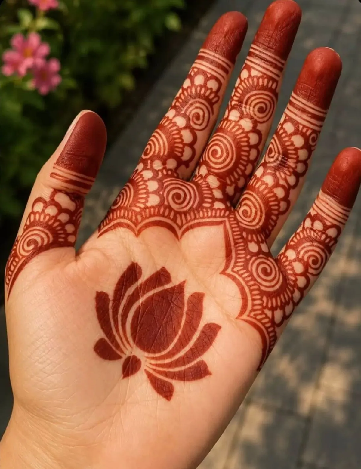Palm henna with a lotus in the center and spirals on every finger, in a deep mahogany stain