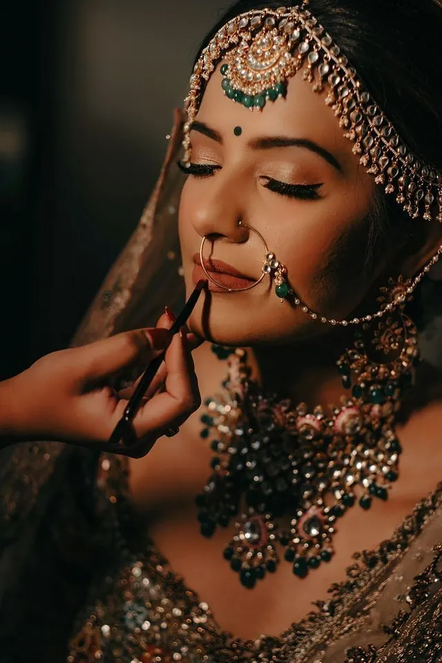 Bride in traditional jewellery having her makeup finished